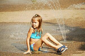 Child sits beside sprinkler