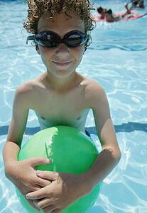 Boy holds ball in pool