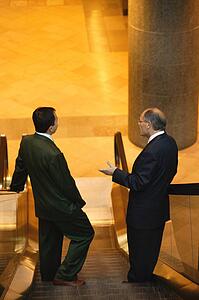 Two men have a conversation on an escalator