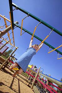Child swinging on Monkey bars at playground