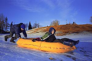 Two boys push a raft down a hill