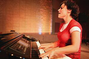 Woman plays the piano and sings