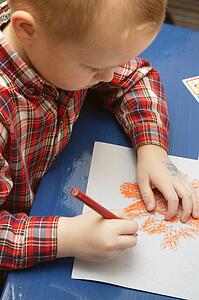 Little boy in kindergarten drawing a Halloween picture in his class