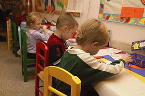 Many children drawing pictures in a kindergarten class