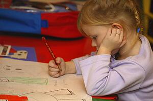 Preschool age girl drawing pictures in kindergarten class