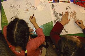 Two girls drawing Halloween pictures in their kindergarten class