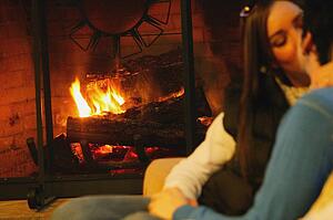 Couple kiss in front of fireplace