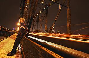 Man sits on side of bridge