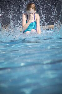 Girl splashes in swimming pool