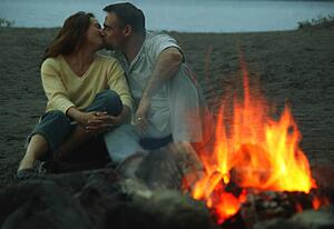 Couple embrace by campfire