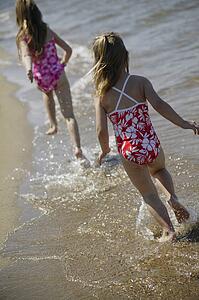 Two children running along the beach