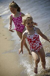 Two children running along the beach