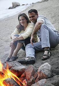 Couple keep warm by campfire