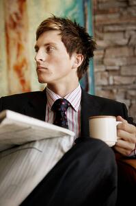 Reading the newspaper and drinking a coffee