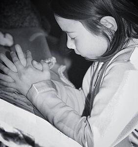 Girl kneeling and praying by bed