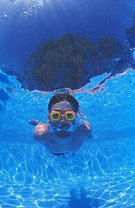 Boy with goggles in swimming pool