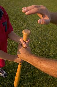 Father and boy's arms with baseball bat