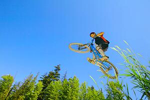 Mountain biker in air against blue sky