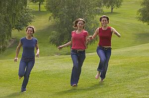 Three teen girls running in park