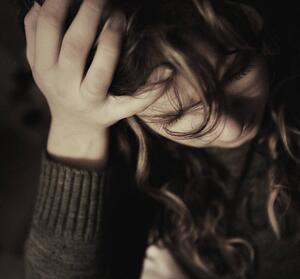 Woman holding head in hand