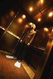 Businessman with snorkel & flippers on in elevator