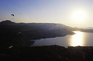Para gliders in flight over lake