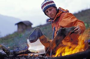 Man drying socks by campfire
