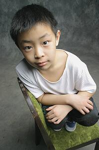 Young boy perched on chair