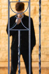 Man behind communion cup on iron fence
