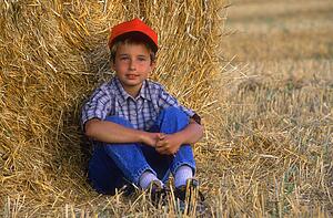 Young boy relaxing in hayfield