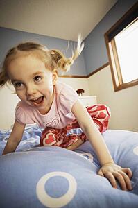 Young girl bouncing on bed