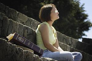 Bible in foreground with woman in background