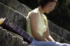 Bible in foreground with woman in background