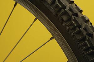 Part of a bicycle wheel against a yellow background