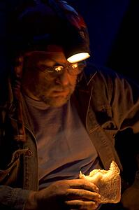 Man eating sandwich in dark with help of headlamp