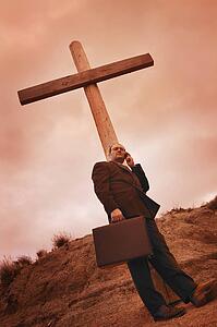 Businessman on phone leaning on a cross
