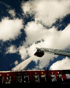 Firemen spraying water from ladder above building