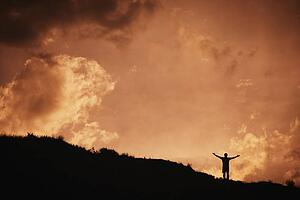 Silhouette of man standing with arms outstretched