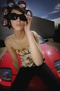 A young woman sitting on the hood of a sports car