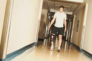 A young man walking with a knee brace in a hospital