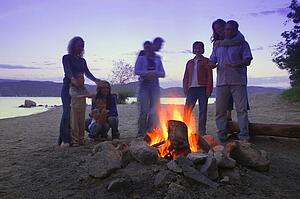 A group of friends and family around a bonfire on the beach