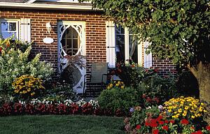 Front entrance of a home with flower gardens in the foreground