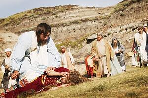 Crowd watches as Jesus helps person lying on ground