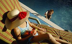 Boy spraying woman sunbathing