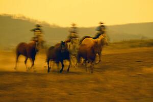 Cowboys on horseback herding running horses, Ponderosa Ranch, soft focus.