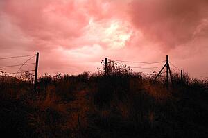 Dark sky over fenced in field