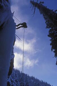 Person scaling frozen waterfall