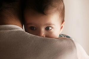 Baby peering over dads shoulder