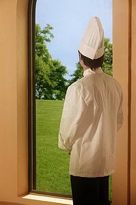A chef looking outside a window