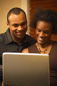 A couple views a laptop screen together